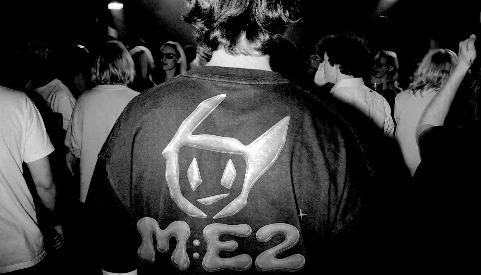 Wide back view of an M:E2 identity shirt